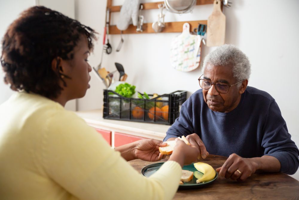 A support worker sitting with an older man at his kitchen table
